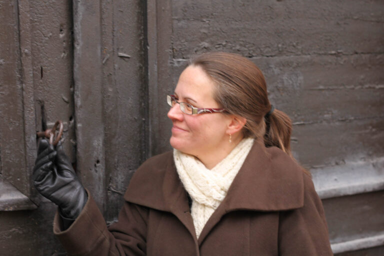 Heli Reinivuo seisoo vanhan oven edessä ja katsoo lukkoa.